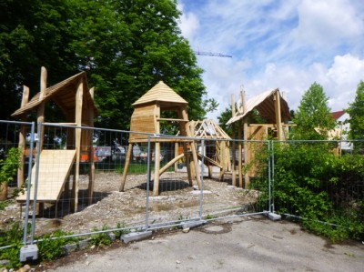 Kinderspielplatz mit Geräten aus Holz zwischen Bäumen im Stadtpark am Wuhrloch