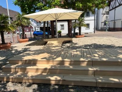 Sand und Holzsteg mit Sonnenschirm beim Stadthausplatz