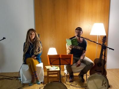 Klaus Zeh und Adeline sitzen zusammen in einem Raum mit Mikrofon und einem Buch