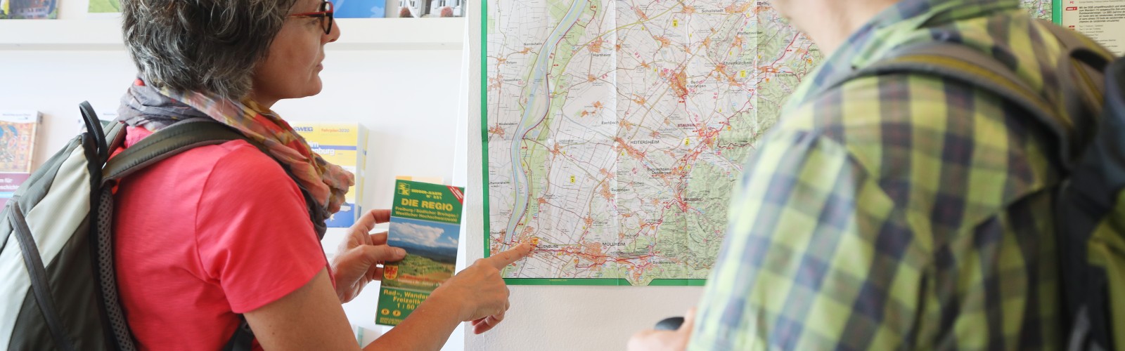Zwei Wanderer betrachten eine Wanderkarte an der Wand