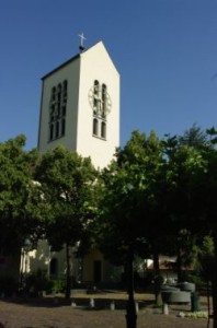 Glockenturm der katholischen Liebfrauenkirche mit Vorplatz und Bäumen