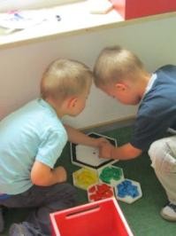 Zwei Kinder spielen am Boden mit einem Steckspiel