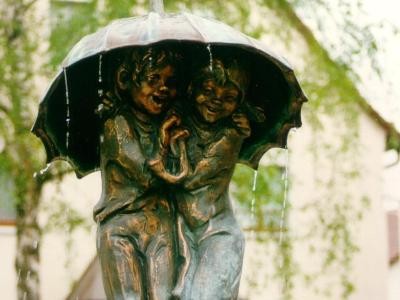 Brunnen mit zwei Kindern unterm Regenschirm