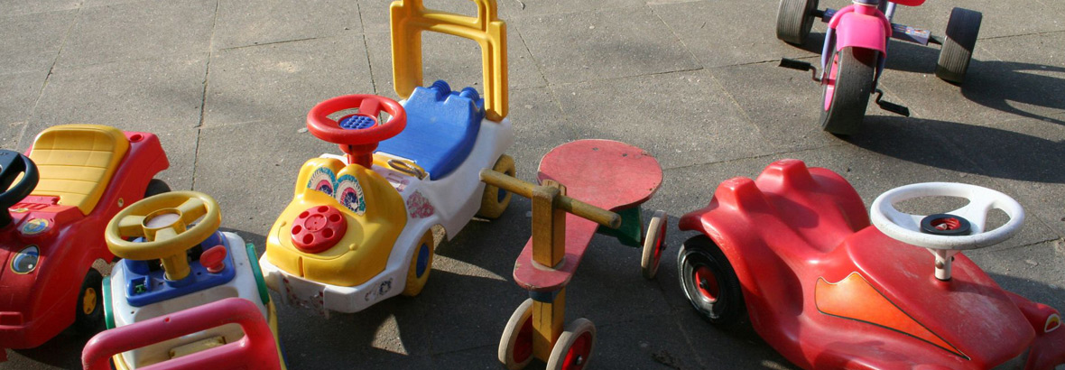 Sechs bunte Kinderfahrzeuge, (Autos, Dreiräder und Bobbycar)